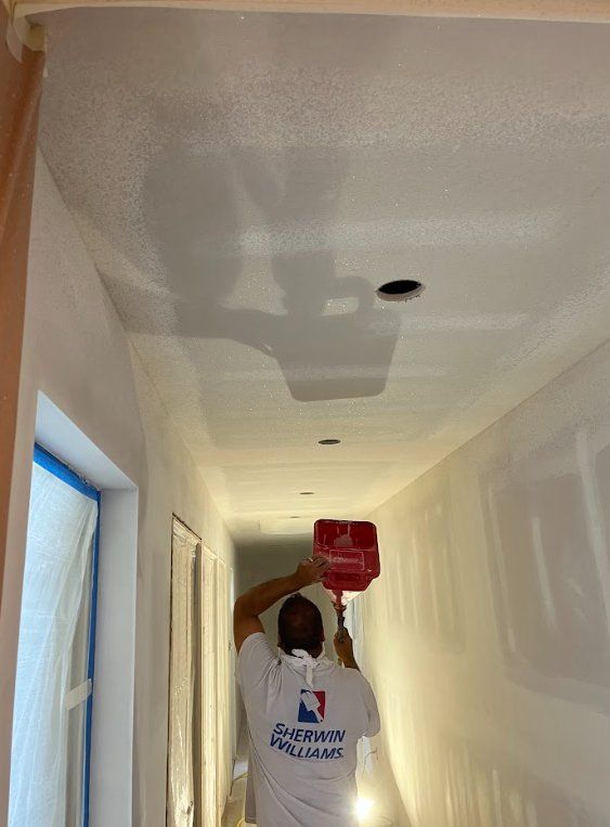 Painter applying ceiling texture in a hallway