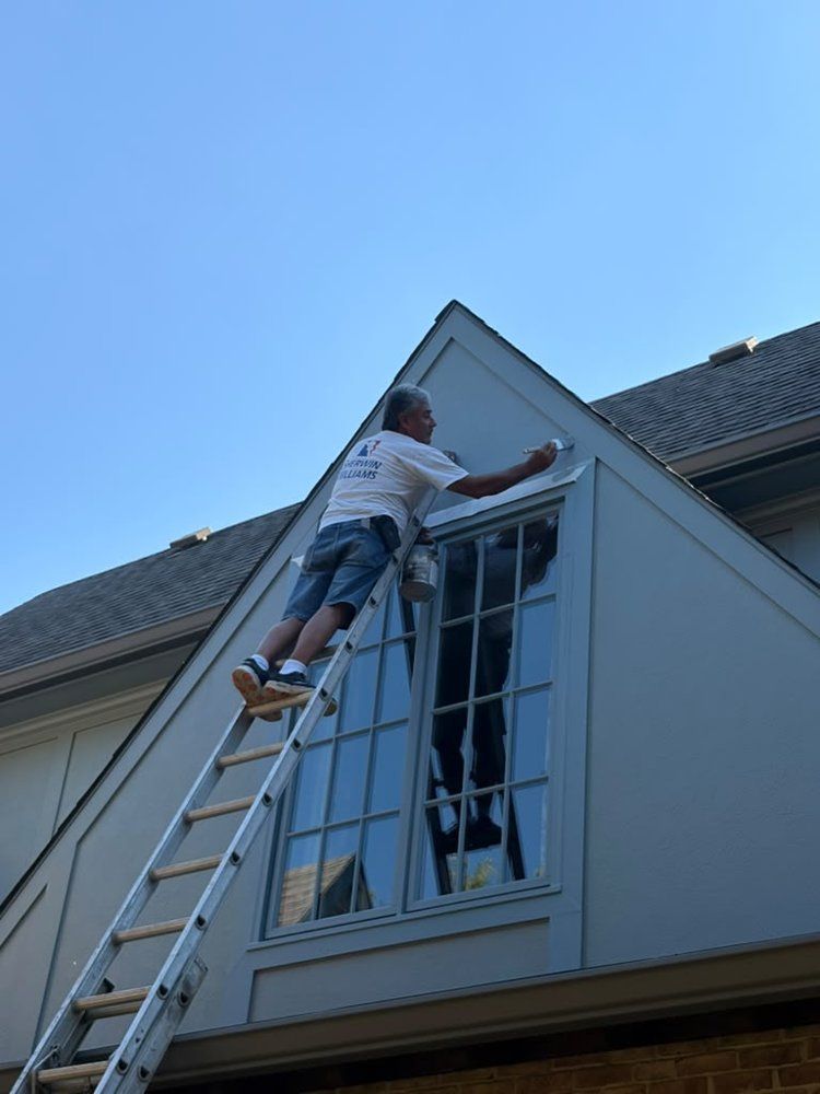 Lakeside painter on a ladder painting exterior window trim