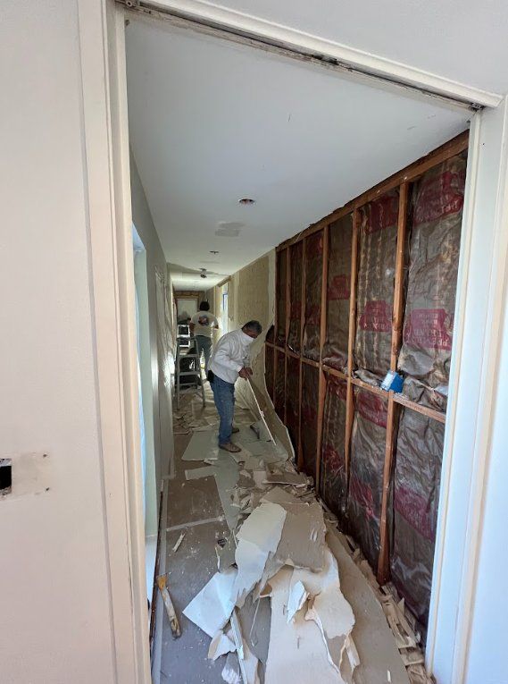 Team removing damaged drywall in a hallway